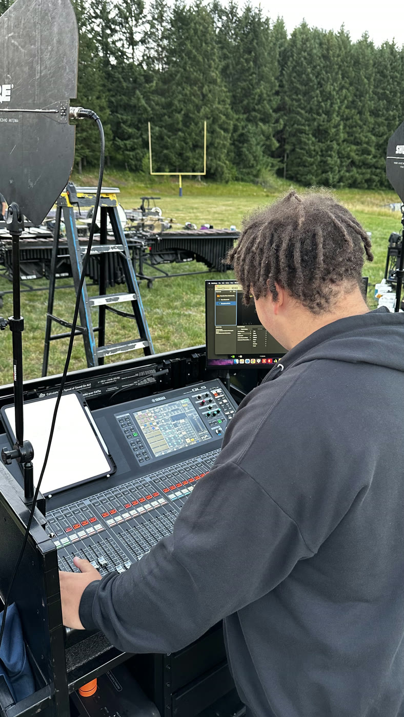 Aaron Battle mixing a drum corps front ensemble on a Yamaha QL5 console at a field rehearsal