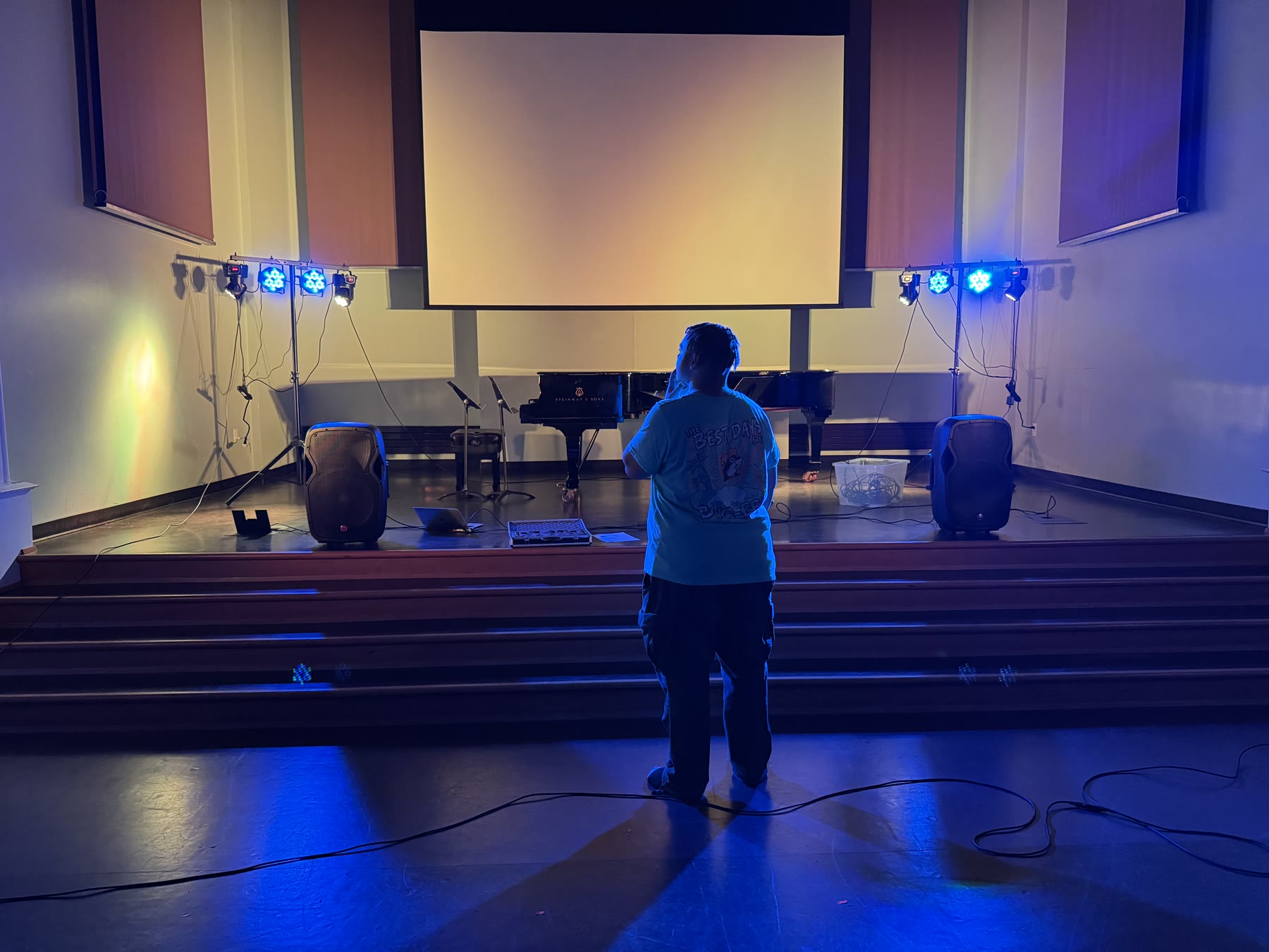Aaron Battle programming stage lighting in a blue-lit auditorium